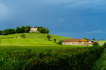 Fototapeta na wymiar F, Burgund, dramatische Gewitterstimmung im Frühjahr bei Château d'Uxelles mit grünen Weiden, Schloß und dunklem Himmel