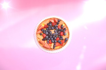 Crostata with berries and fruits on the rose coloured bacground