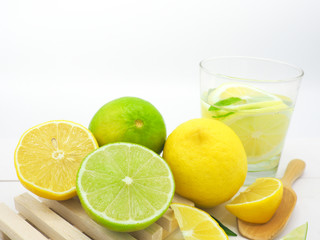 Fresh lemon slice and lime with lemon in water on white wood background