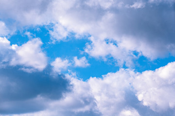 Background of transparent white clouds in a light blue sky illuminated by the sun.