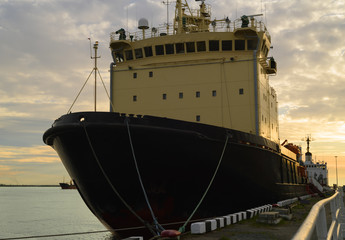 Fototapeta premium The icebreaker is moored in a port at sunset. The huge icebreaking vessel is on a mooring during navigation.