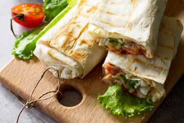 Shaurma, cut in half, shaurma doner, meat with vegetables in a bread cake, on a light stone or concrete background. Concept restaurant fast food.