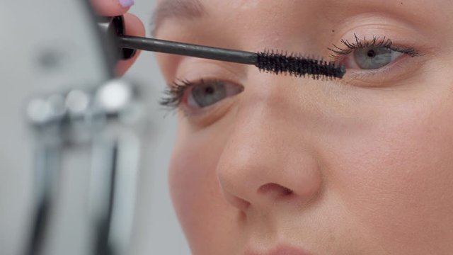 closeup macro of woman's eye put maskara on lashes side view