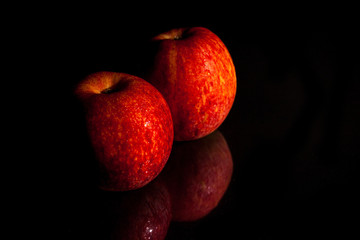 The apple red on the glass, black background.