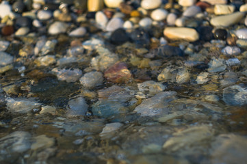 pebble stones on the sea beach, the rolling waves of the sea with foam