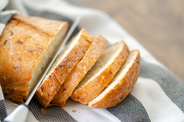Fresh bread slice and cutting knife on wooden table