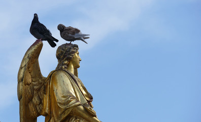 Fototapeta premium Golden angel statue with two doves on the head