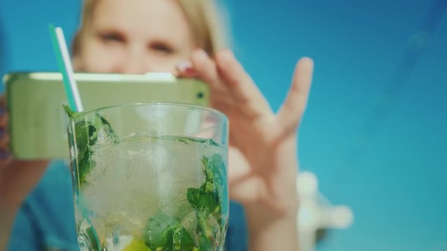 A woman blogger is photographing a glass with a cocktail. Restaurant critic