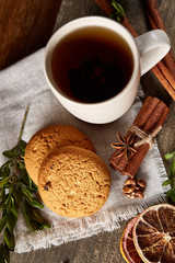 Christmas composition with pile of cookies, cinnamon and dried oranges on light wooden background, close-up.