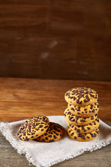 Stacked chocolate chip cookies on white homespun napkin in country style, selective focus.