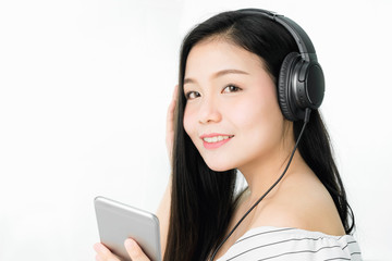 Asian Women are listening to music from black headphones. In a comfortable and good mood, on a white background gives a soft light.