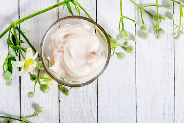 cosmetic cream and white wildflower on bright wood table background