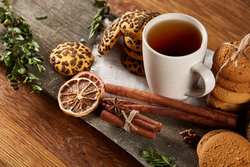 Traditional Christmas tea concept with a cup of hot tea, cookies and decorations on a wooden table, selective focus