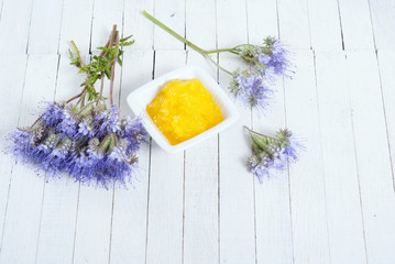 crystallized phacelia honey and flowers on white wooden background