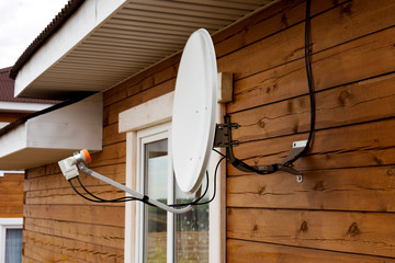 Satellite dish on the wall of the house.