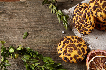 Christmas composition with pile of cookies, cinnamon and dried oranges on wooden background, close-up.