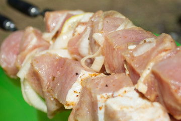 pieces of raw shish kebab meat on skewer with onion and lemon
