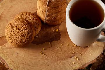 White cup of tea and cookies on a log over country style wooden background, close-up, selective focus