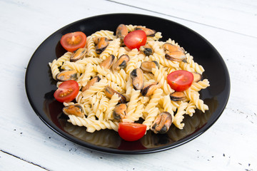 Italian pasta with mussels and tomatoes in a black plate