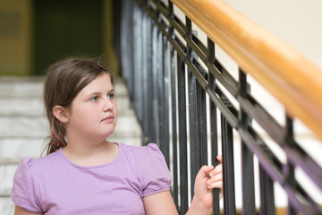 Portrait of a girl sitting on the stairs next to the iron railing