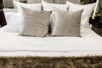 Bed maid-up with clean white pillows and bed sheets in beauty bedroom.