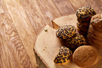 Sweet assortment of biscuits on a round wood log over rustic wooden background, close-up, selective focus.