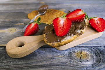 croissant with chocolate pasta and strawberries on an old wooden background