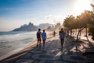 Papier Peint photo autocollant Brésil People walk on the famous sidewalk of Ipanema beach by sunset