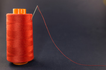 Red thread with a needle on a blue background