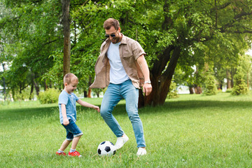 father and son having fun and playing football at park