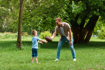 Naklejka na ściany i meble happy father and son playing american football at park