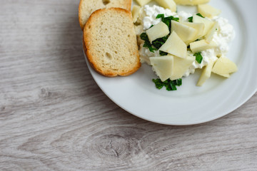Natural delicious breakfast. Fried slices of baguette with curd, apple slices and parsley on a white plate, wooden background