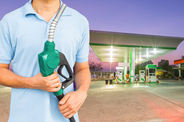 Man hold fuel nozzle to add fuel in car at gas station.