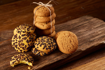 Sweet assortment of biscuits on a round wood log over rustic wooden background, close-up, selective focus.