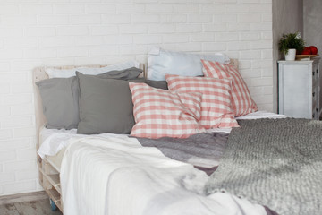 Bed with gray and red pillows, gray plaid