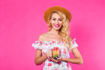 Obraz na płótnie Canvas Portrait of young woman holding tasty fresh fruit in bottle on pink background