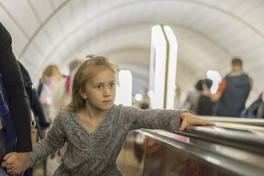 little girl is riding an escalator