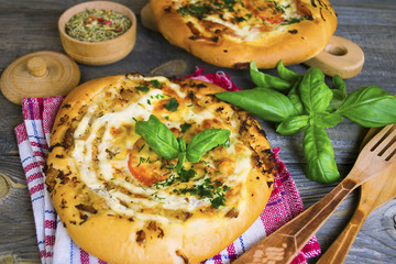 homemade little pizza with cheese and greens on an old wooden board
