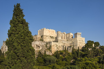 Fototapeta na wymiar Greece, Athens: Panoramic view of famous Acropolis with people who visit the Parthenon, Erechtheum, Beule Gate and Temple of Athena in the city center of the Greek capital and blue sky. April 26, 2018