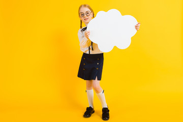 Girl with red pigtails on a yellow background. A charming girl in round transparent glasses is holding a white cloud in her hands.