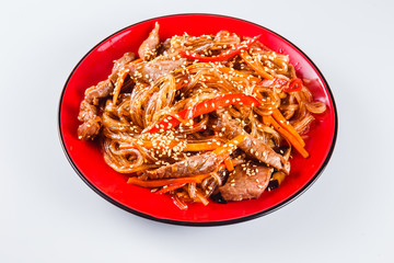Noodles with  beef, pepper and sesame seeds on a red plate on a white background. Traditional Italian pasta. Close