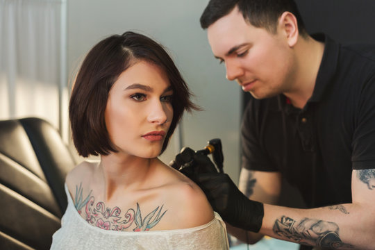 Tattoo artist working with needle on clients body