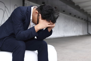 Depressed tired young Asian business man in suit bend down head