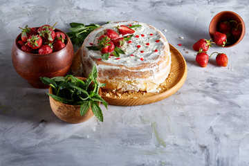 Delicious still life with strawberry tart covered with whipped sour cream, strawberry and mint on white background.
