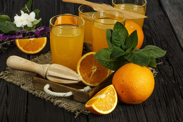 Obraz na płótnie Canvas Fresh orange juice with mint in a glass bowl on a dark plate. Orange juice on a dark background, top view, copy space.