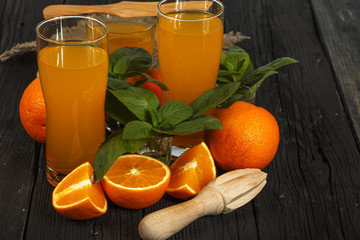 Fresh orange juice with mint in a glass bowl on a dark plate. Orange juice on a dark background, top view, copy space.