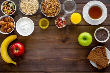 Set of products for healthy vegetarian breakfast. Fruits, oatmeal, yogurt, nuts, crispbreads, chia on dark wooden background top view space for text