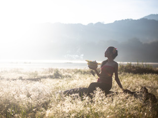 Bali girl poses while wearing traditional sarong in native pattern with nice lake in the background / travel concept / Indonesia /Rim light