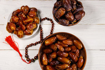 Dates fruit and rosary on white wooden table. Top view