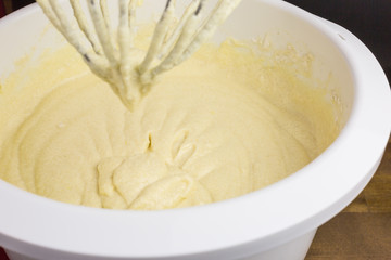 cake batter of butter, eggs, sugar, milk and flour in  a mixing bowl, focus on batter  in the bowl